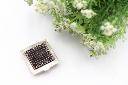 Caixa de comprimidos em prata de formato quadrado e com aplicações de rosinhas